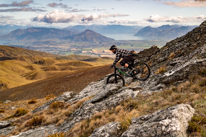 A biker barreling down a rocky trail on a mountain in New Zealand.